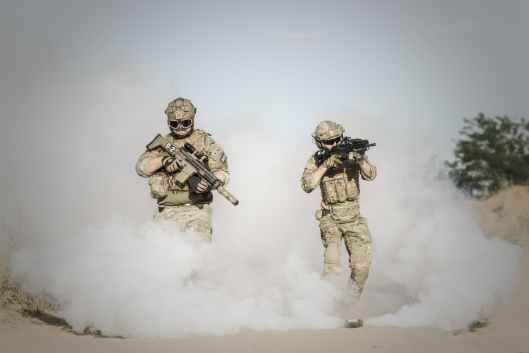 men holding rifle while walking through smoke grenade